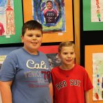 Room 4 students pose in front of their self portraits