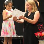 A Room 2 student celebrates her end of year award with her teacher