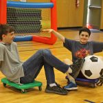 Our 8th grade helpers join in a game of scooter board soccer