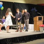 An 8th grade student receives his diploma